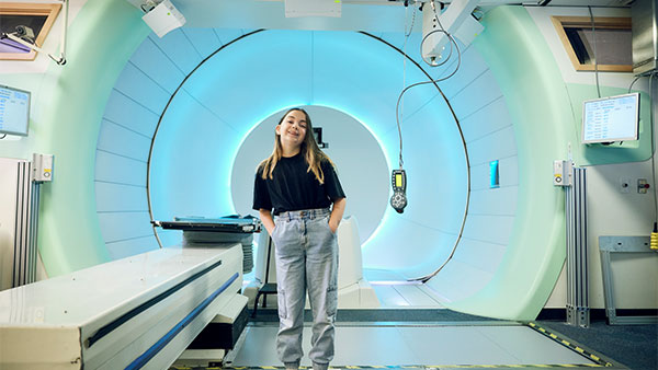 Smiling child stands in front of a proton beam therapy machine Smiling child stands in front of a proton beam therapy machine