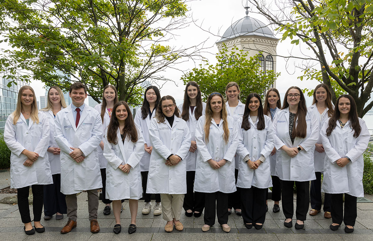 The 2024 Pharmacy residents posing in lab coats in a courtyard, with trees and a cupola behind them.