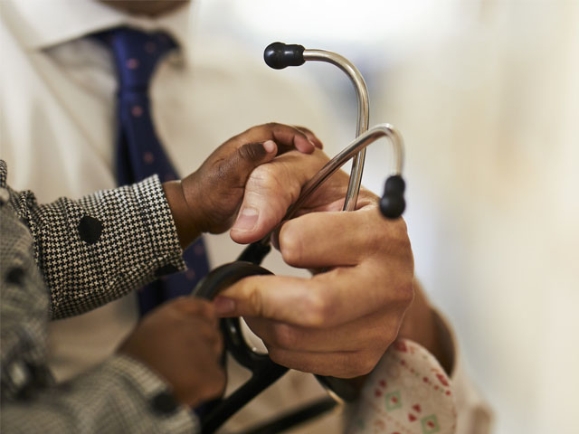 A doctor's and child's hands holding a stethoscope.